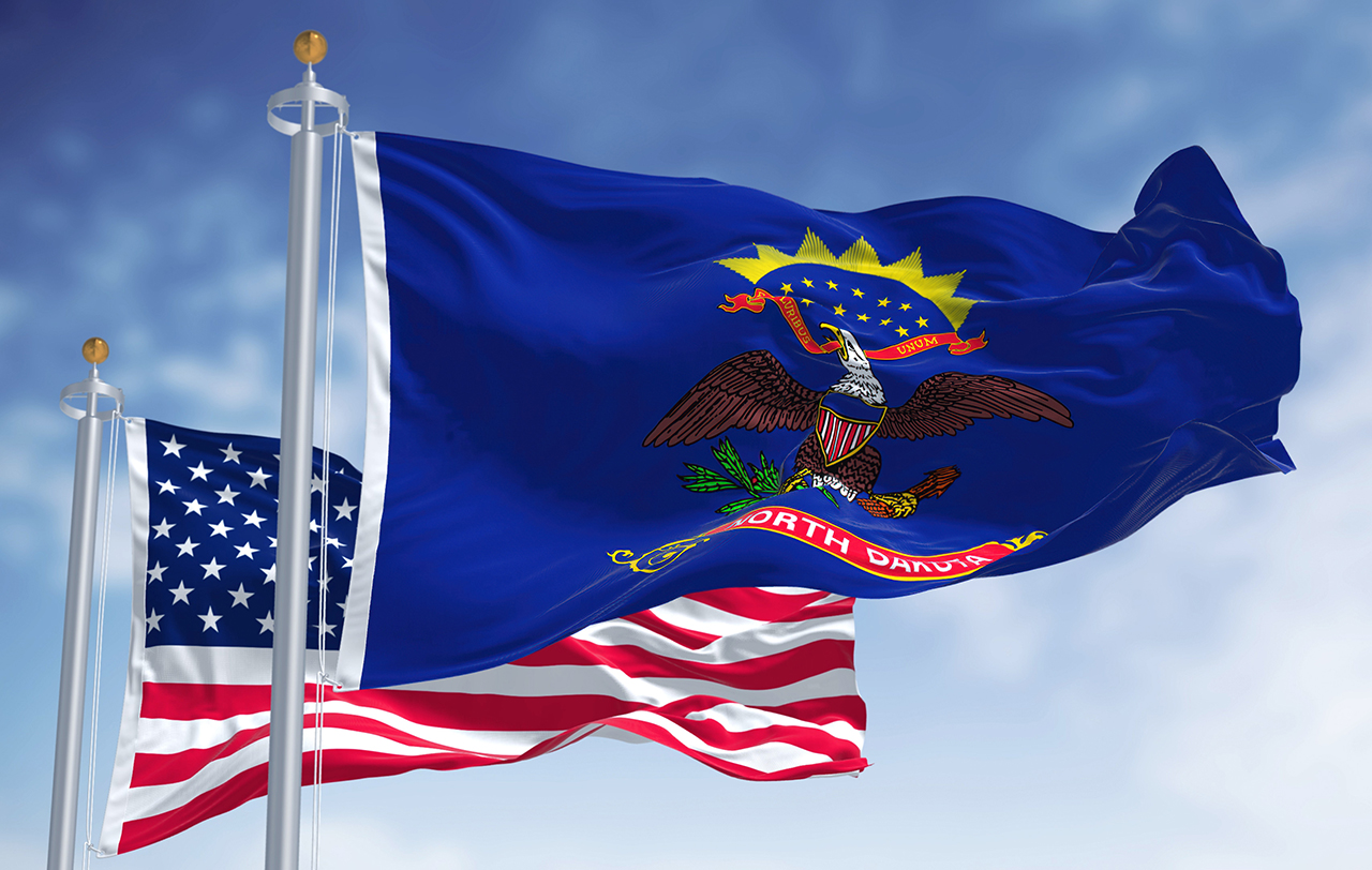The North Dakota state flag waving along with the national flag of the United States of America.