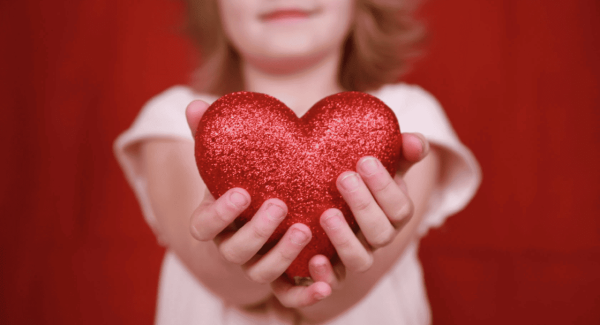 an anonymous girl holding a sparkly heart forward