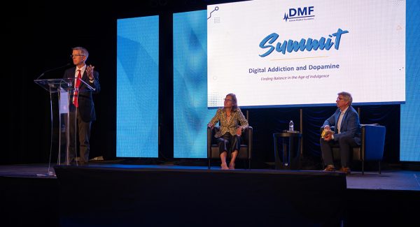 DMF Inaugural Summit 2023 • Pat Traynor at the podium with Dr. Anna Lembke and Kevin Wallevand seated behind